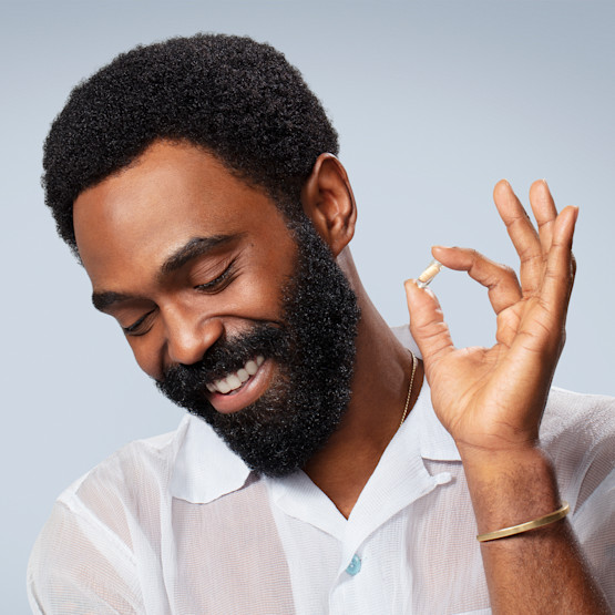 Man smiling and holding Synbiotic pill