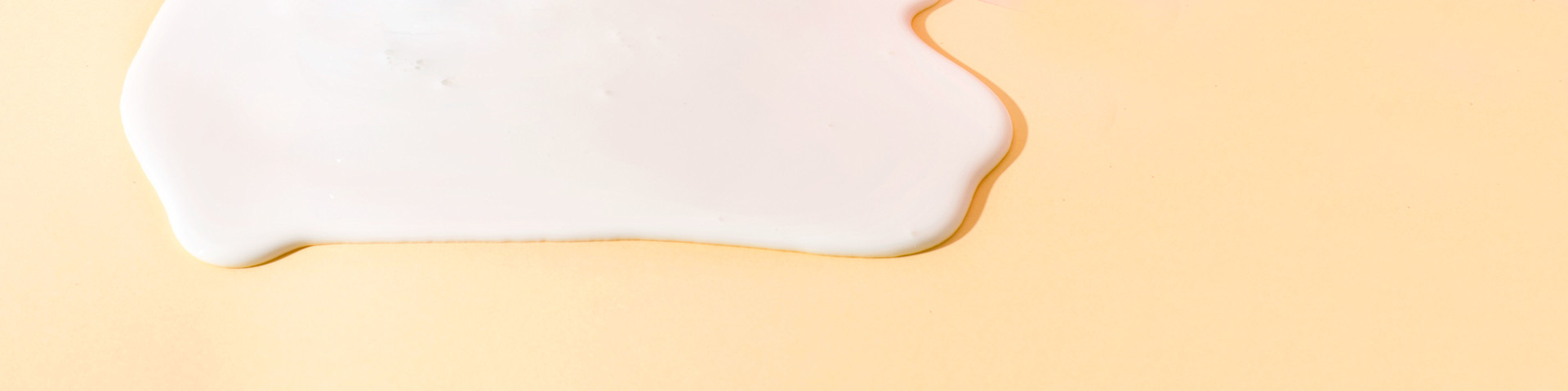 Closeup of calcium as a white liquid on a peach-colored background.