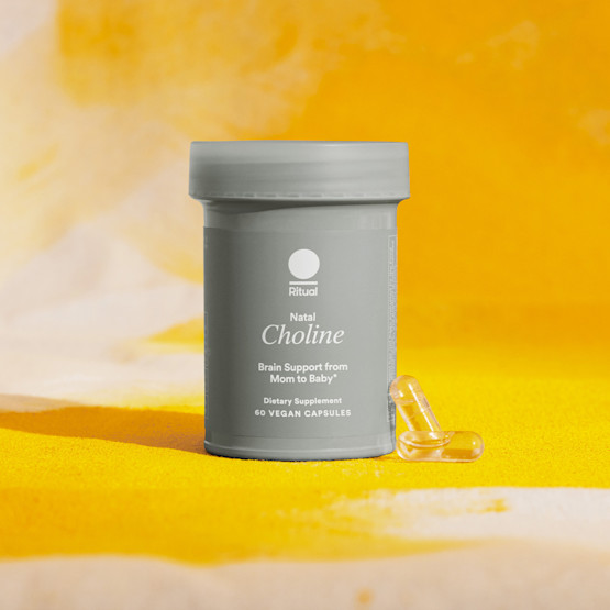 Bottle of Natal Choline with two clear pills and a yellow backdrop