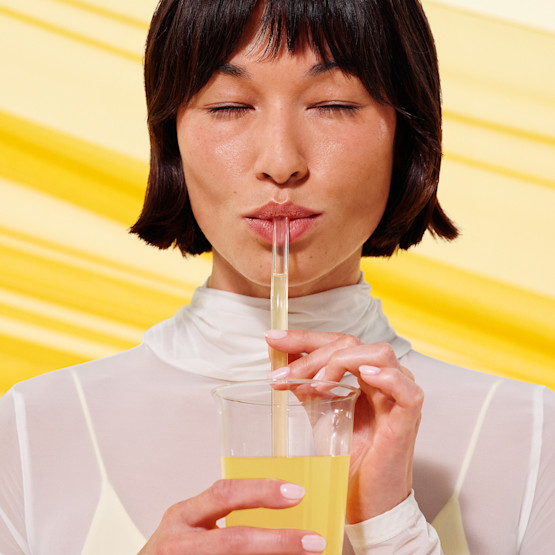 Model drinking Fertility Support drink mix from a glass through a straw.