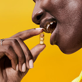 Model holding a Stress Relief capsule in front of their mouth.