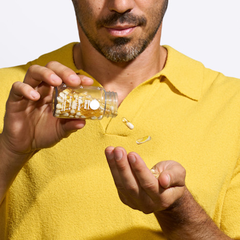 Male in yellow shirt pouring bottle of Essential for Men 18+ into his hand.