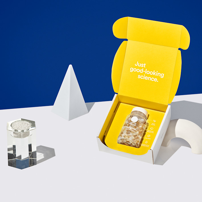 Box with Essential for Women 50+ with a glass of water and two pills.