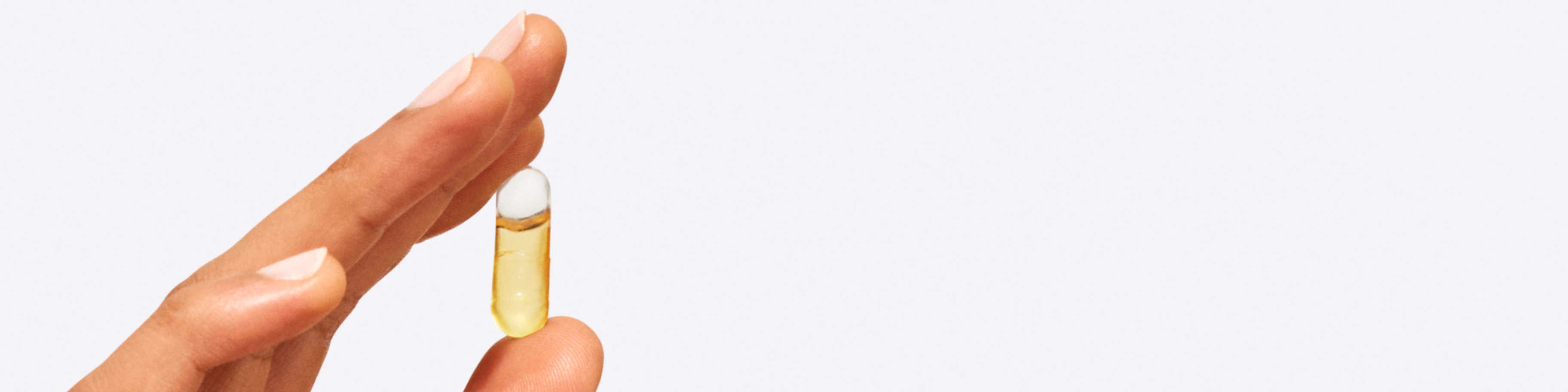 Ritual's Omega-3 DHA + EPA Capsule held between a thumb and index finger.